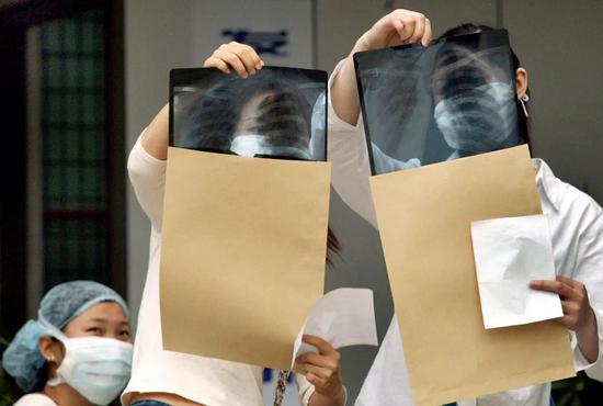  2003年5月14日，在杭州市中医院发热门诊就医的两位感冒患者正急迫地察看自己的X光片中有无肺部感染的迹象