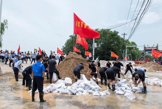 在城区西坝口,党员干部与群众一起参与防汛抢险。记者 何希斌 摄