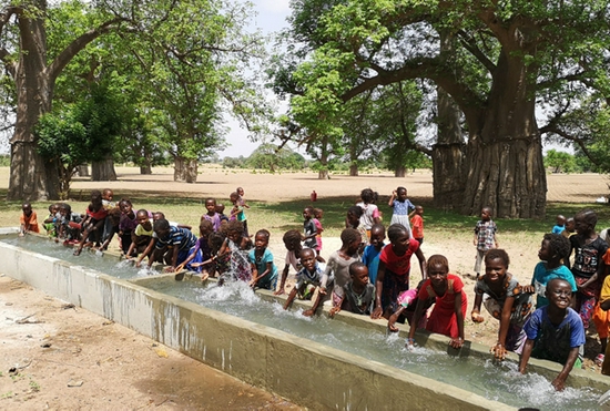 2019年7月15日，在塞内加尔中部坦巴昆达大区一处村庄，当地村庄的儿童在刚刚建好并灌满干净井水的牲畜饮水槽戏水。