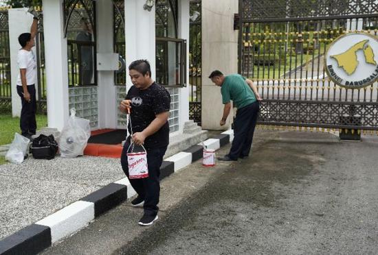 工人沙斯旺（中间）在努洛伊曼王宫大门外粉刷和清洗地面。新华社记者毕晓洋摄