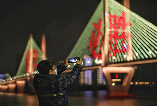  灯光维修师温瑞在雨夜中拍照记录武汉长江二桥灯光情况（2月28日摄）。新华社发