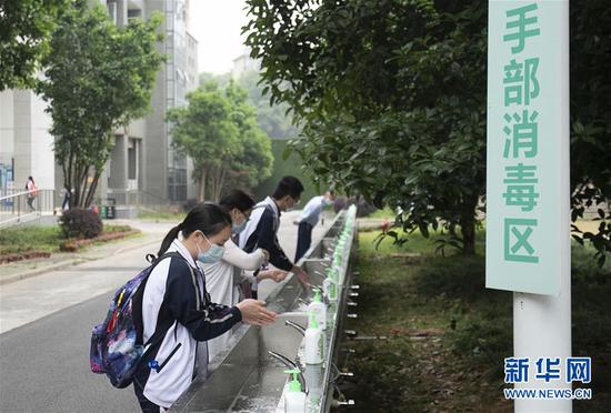5月6日，武汉首批121所学校高三年级正式复学。在湖北省武昌实验中学，高三年级的学生入校后在手部消毒区洗手。  新华社记者 熊琦 摄