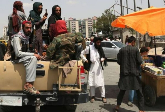 8月17日，阿富汗塔利班成员在喀布尔街头向小贩购物。新华社