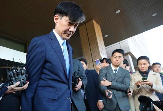2019年10月14日，在韩国果川，韩国法务部长官曹国（左）离开政府办公大楼。新华社 图