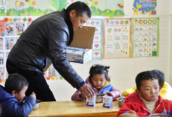 ↑2020年11月25日，西藏山南市贡嘎县吉雄镇红星社区双语幼儿园的老师为孩子们分发牛奶。