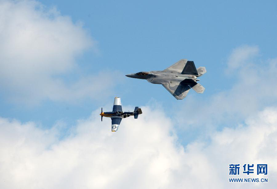 2015年9月19日，在美国首都华盛顿附近的安德鲁斯空军基地，一架F-22猛禽战斗机（上）与一架P-51野马战斗机进行飞行表演。