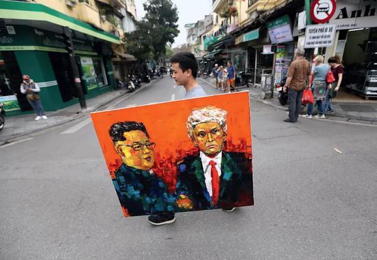 2月27日“金特会”前夕，越南河内街头一名男子举着金正恩和特朗普的油画。图/ 视觉中国