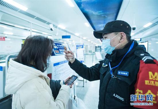  1月23日上午，在武汉地铁8号线汪家墩站，工作人员对旅客进行体温检测。新华社记者 肖艺九 摄