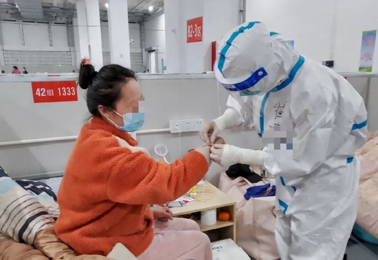  崔媛在上海临港方舱医院内为患者佩戴腕带。（受访者供图）