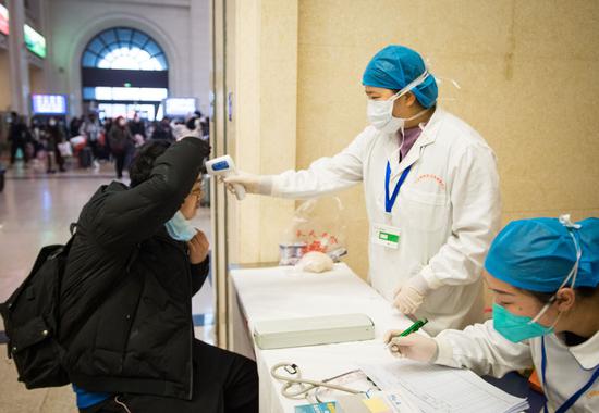 ↑ 2020年1月22日，在汉口火车站，医护人员对进站旅客的体温进行检测。