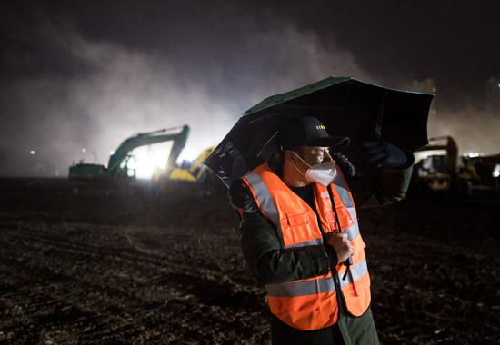 ↑ 2020年1月24日,在武汉火神山医院建设工地,施工交通指挥员郭胜和在指挥机械车辆。