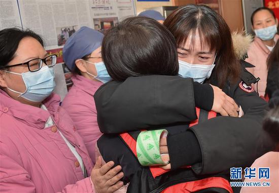 1月26日，在北京医院，同事拥抱送别援鄂抗疫医疗队队员（背红色背包者）。新华社发（彭子洋 摄）