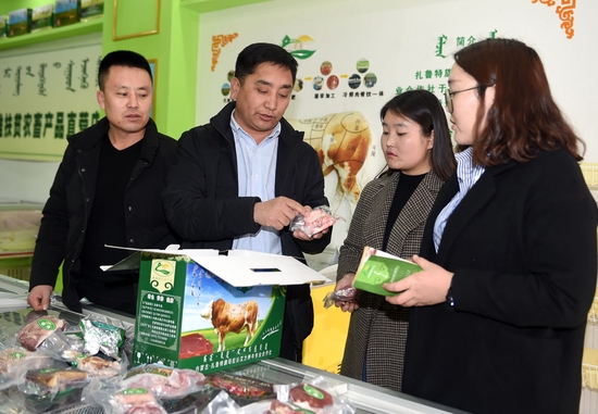 这是吴云波（左二）在内蒙古自治区扎鲁特旗鲁北镇的销售店向顾客介绍合作社的牛肉产品（2018年2月26日摄）。新华社记者任军川摄