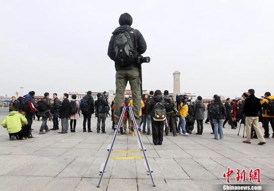 资料图：站在梯子上的摄影记者。田贺 摄 图片来源：CFP视觉中国