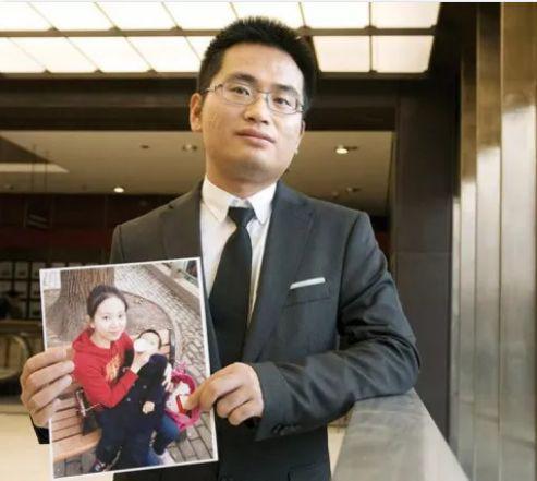 身亡产妇的丈夫举着妻子和大儿子的照片(图自美国中文网)