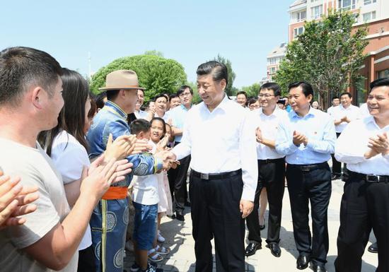  15日，习近平在赤峰市松山区兴安街道临潢家园社区同群众亲切握手。