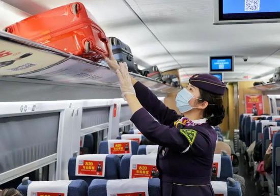 一位高铁列车长在整理行李架上的物品(周围 摄)