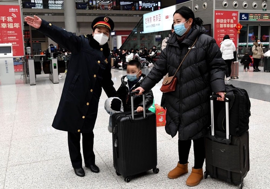  1月18日，郑州东站客运值班员张华（左）在候车大厅内引导旅客。新华社记者 李安 摄