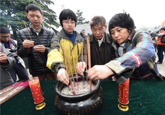 南京大屠杀幸存者常志强（右二）率亲属在侵华日军南京大屠杀遇难同胞纪念馆内的遇难者名单墙前焚香（2015年4月5日摄）。新华社记者 孙参 摄