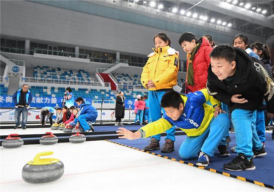  这是2019年12月10日，北京史家实验学校的学生在“冰立方”体验冰壶。新华社记者 鞠焕宗 摄
