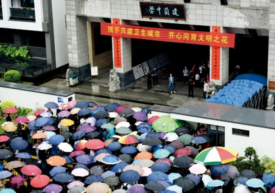  2018年5月5日，浙江杭州市热门民办初中建兰中学举行自主招生面试。临近中午11点，许多家长冒雨守候在校门口。图/视觉中国