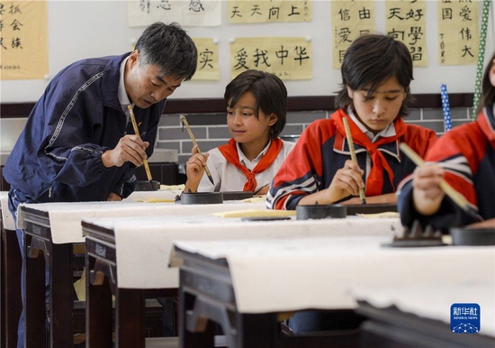 在新疆疏附县托克扎克镇中心小学书法教室内，王庄铁老师在教学生写毛笔字（2017年9月26日摄）。新华社记者 赵戈 摄