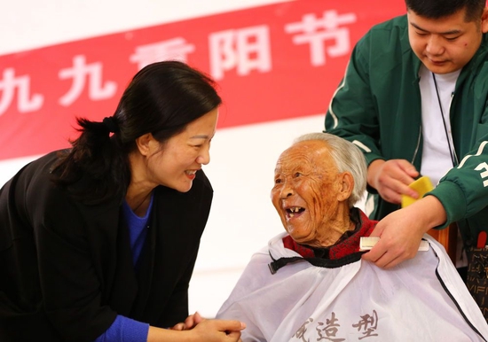  2022年10月4日，在山东省滕州市一家养老院，社会工作者为老人理发。新华社发（李志军 摄）