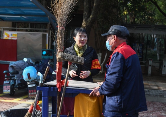  禹诚（左）在武汉市洪山区和平街爱家国际社区了解卫生排班情况（2月19日摄）。新华社记者 程敏 摄