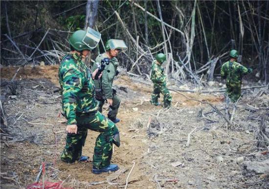 2017年，新华社记者周磊（左一）在云南省麻栗坡县老山雷区拍摄扫雷部队工作场景。