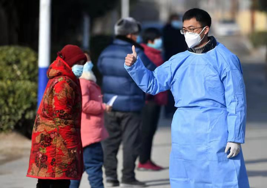 1月15日，河南省禹州市无梁镇曹楼村的志愿者在为排队做核酸检测的村民加油鼓励，图据新华社
