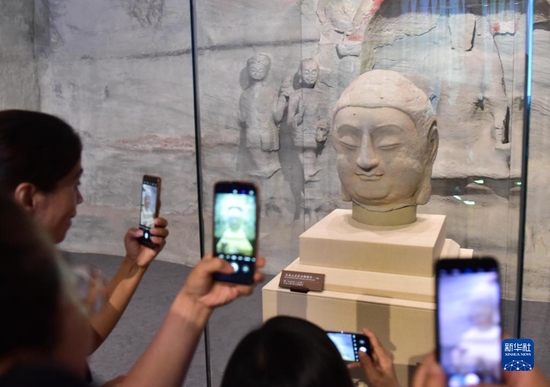 在太原市天龙山石窟博物馆，参观者在拍摄回归的天龙山石窟“第8窟北壁主尊佛首”（2021年7月24日摄）。新华社记者 柴婷 摄