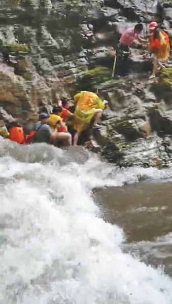 有十多名游客紧贴着峭壁，用手抓着岩石才得以幸存。“我们视频”截图