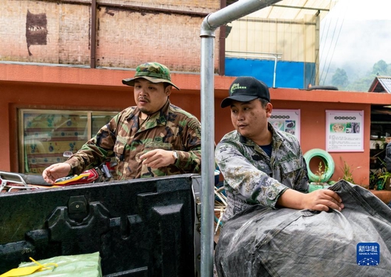 基诺族青年陶建雄（右）往车上装载物资，准备带游客拍摄团队进山踩点（12月12日摄）。新华社记者 陈欣波 摄