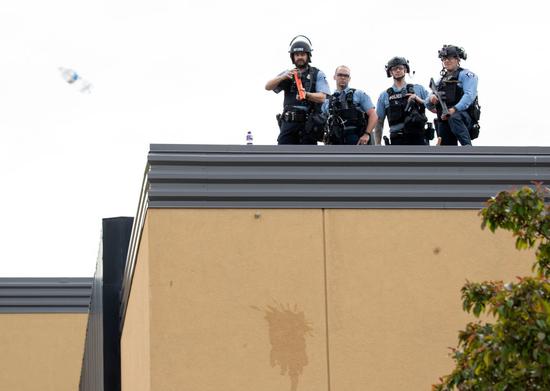 27日，明尼亚波利斯市第三辖区警局屋顶，几名警察在维持秩序。（美联社）