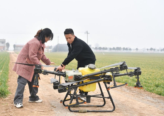 在陕西省宝鸡市陈仓区慕仪镇齐西村的农田，齐叶叶（左）与齐昆调试植保无人机（2023年2月27日摄）。新华社记者 张博文 摄