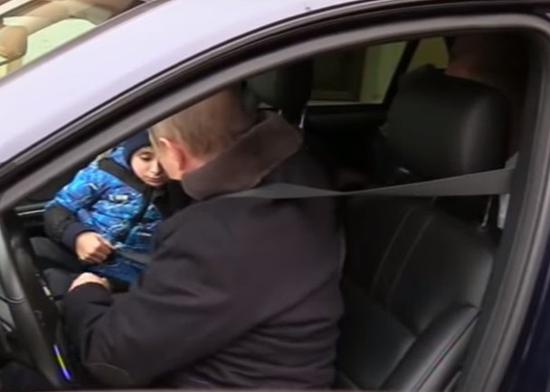 普京亲自驾车，开动前给男孩扣安全带。