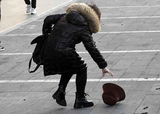  广渠路，一位女士的帽子被吹落。