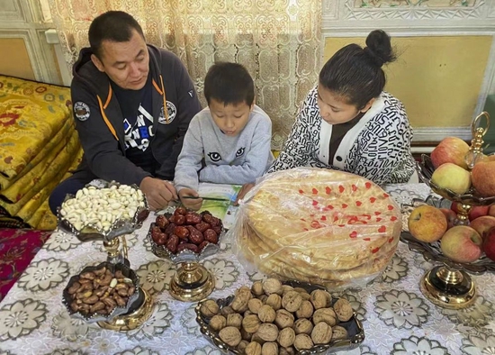 10月16日，新疆喀什古城居民阿依先木姑力·阿布来提（右）在家中辅导孩子功课。新华社发（唐努尔·玉麦尔 摄）