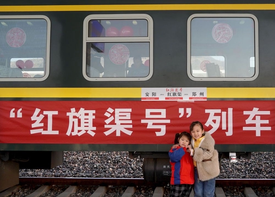 1月20日，在河南林州的铁路红旗渠站，两名小朋友在“红旗渠号”列车旁留影。新华社记者 李安 摄