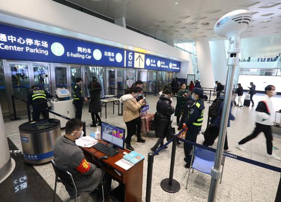 ↑ 2020年1月21日，在武汉天河机场，工作人员对旅客进行体温检测。