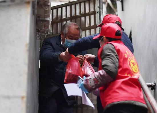 2月7日，武汉市江岸区社区工作人员为一独居老人送去体温计和蔬菜