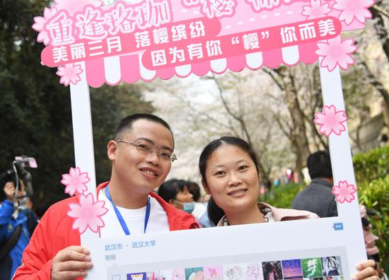 3月13日，来自广东省茂名农垦医院的李胜华（左）带着妻子在武汉大学樱花大道赏花留影。去年2月9日，李胜华援鄂到武汉东西湖方舱医院工作。