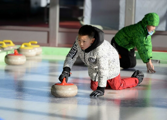 2017年1月9日，在黑龙江省冬季群众体育活动基地，一名小学生在学习掷冰壶。新华社记者王凯摄