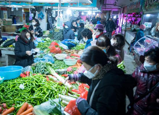 ↑ 2020年1月23日，在武汉宏祥路生鲜市场，市民在挑选菜品。