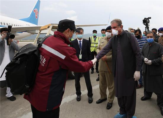 3月28日，在巴基斯坦伊斯兰堡国际机场，巴基斯坦外长库雷希（前右）与刚刚抵达的中国政府赴巴基斯坦抗疫医疗专家组成员握手。新华社记者 刘天 摄