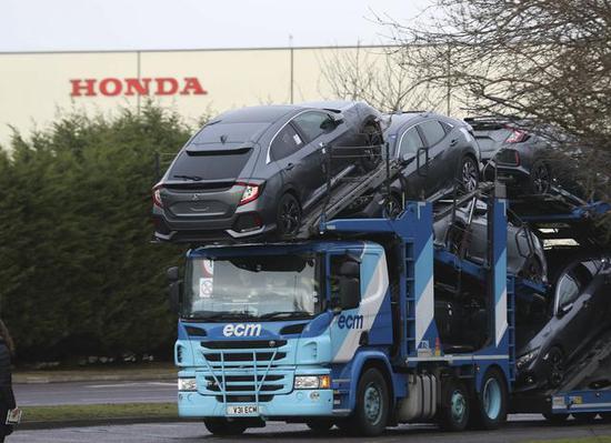  英国斯温登，一辆满载汽车的运输车驶离本田汽车工厂。（新华社）