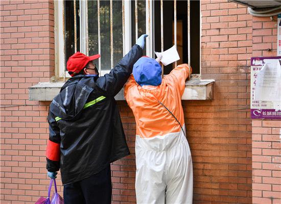 2月23日，武汉市武昌区华锦社区的志愿者从窗口为一名行动不便的老人递爱心菜。新华社记者 程敏 摄