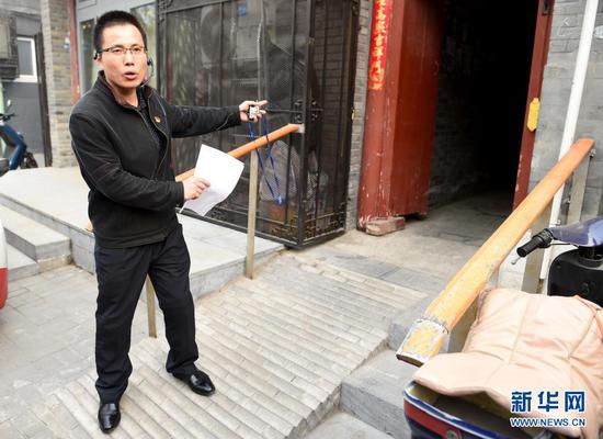 在北京市西城区,街巷长王俊礼在西河沿街218号门前介绍改造坡道、方便院内居民出行情况(2018年4月2日摄)。新华社记者 罗晓光 摄