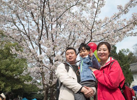 3月13日，辽宁援鄂医疗队丹东市中心医院护士李杰（右）与家人在武汉大学樱花树下合影。