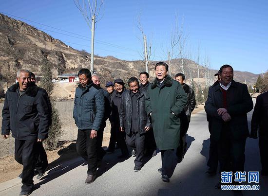  2015年2月13日，农历羊年春节来临之际，习近平在陕西延安市延川县文安驿镇梁家河村调研时同村民边走边聊。新华社记者 兰红光 摄